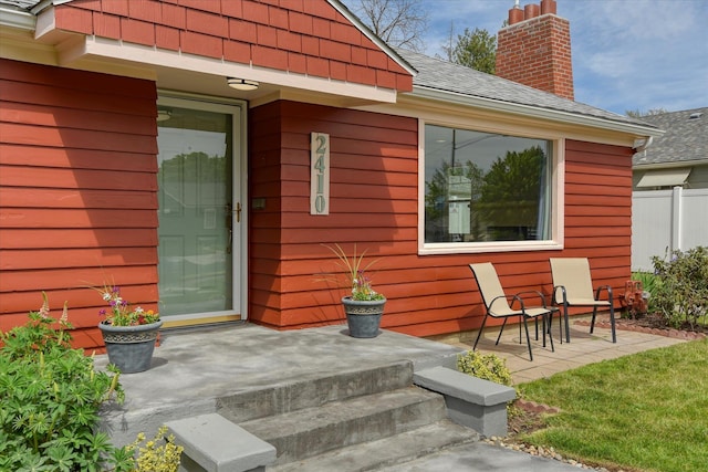 2410 W Upton Ave, Spokane, WA 99205 - view of exterior entry featuring fence, roof with shingles, a chimney, and a patio