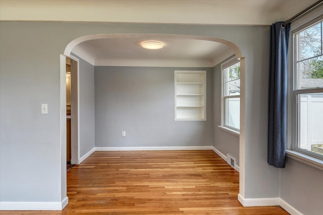 2410 W Upton Ave, Spokane, WA 99205 - spare room featuring arched walkways, light wood-style flooring, healthy amount of natural light, and baseboards
