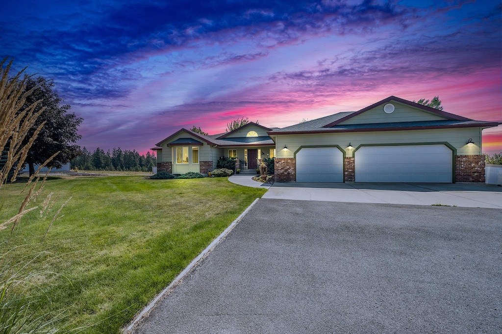 67 E Stutler Rd, Spokane, WA 99224 - ranch-style house with driveway, an attached garage, a lawn, and brick siding