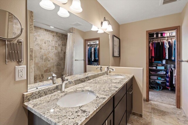 17206 W Buckboard Ave, Medical Lake, WA 99022 - full bathroom with a spacious closet, double vanity, baseboards, a tile shower, and stone finish floors