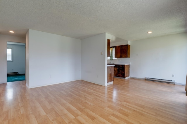 1514 3rd St, Cheney, WA 99004 - unfurnished living room featuring baseboard heating, light wood-style flooring, recessed lighting, a textured ceiling, and a baseboard heating unit