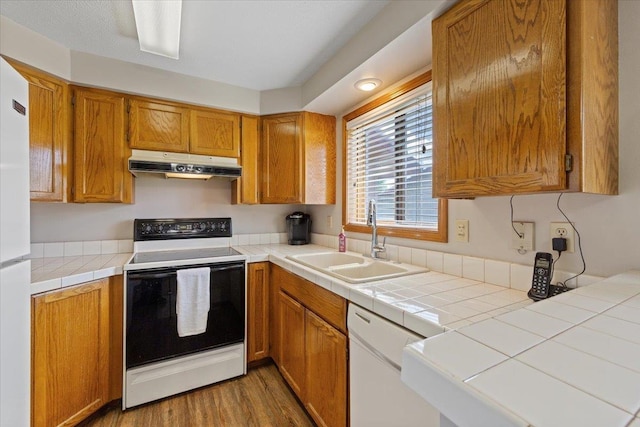 3716 S Alder Cir, Spokane, WA 99223 - kitchen with under cabinet range hood, white appliances, a sink, wood finished floors, and brown cabinetry