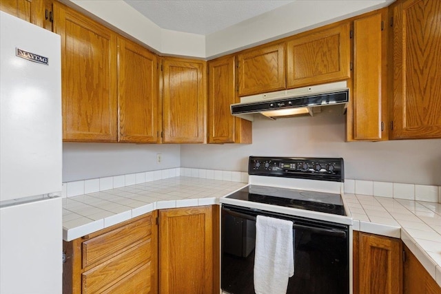 3716 S Alder Cir, Spokane, WA 99223 - kitchen with freestanding refrigerator, range with electric stovetop, under cabinet range hood, and brown cabinets
