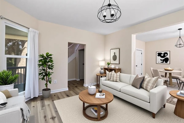 living area with light wood-style flooring, a chandelier, and baseboards