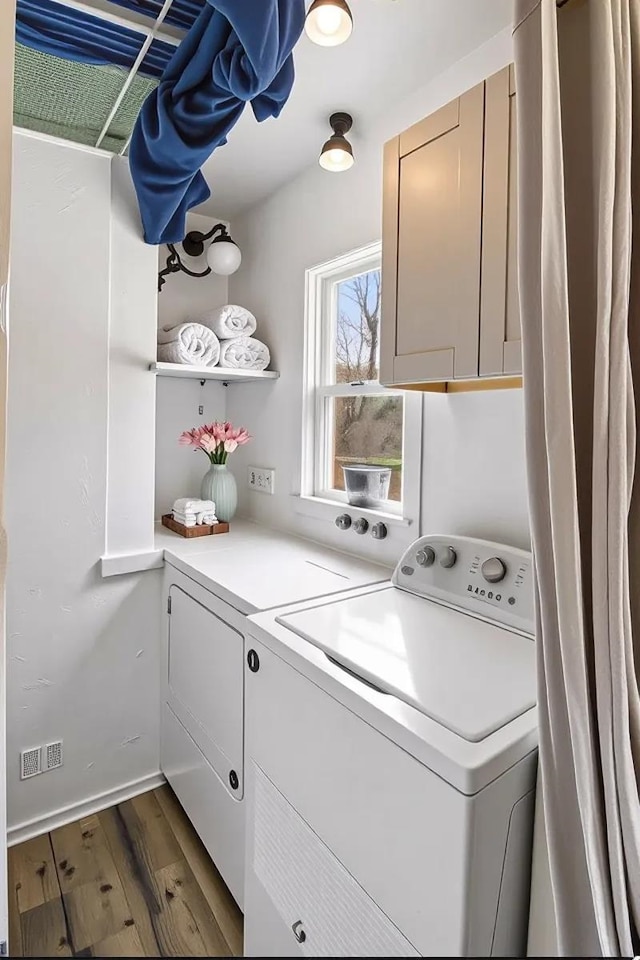 laundry room featuring washer and dryer, cabinet space, and dark wood-style floors