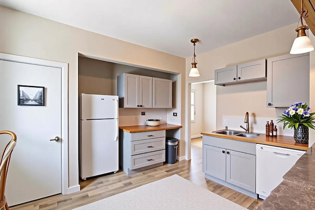 kitchen with white appliances, a sink, gray cabinetry, decorative light fixtures, and light wood-type flooring