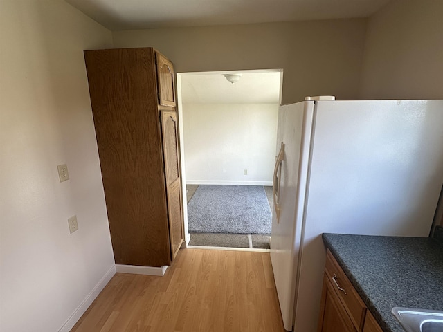 2304 W Glass St, Spokane, WA 99205 - kitchen featuring light wood-type flooring, white refrigerator with ice dispenser, baseboards, dark countertops, and brown cabinetry