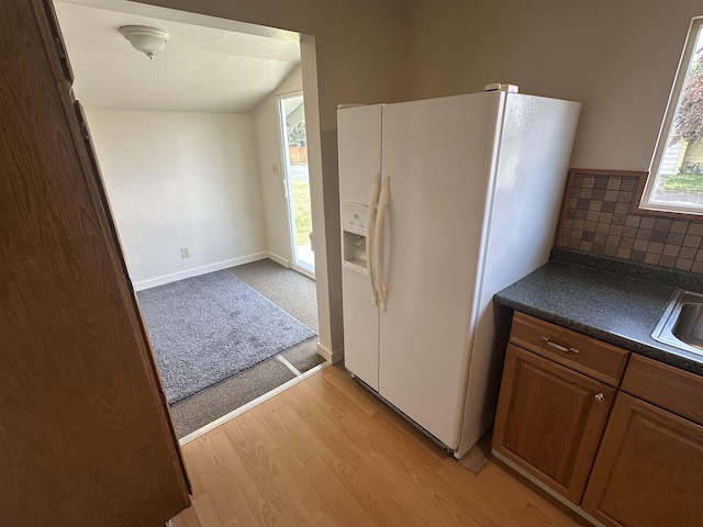 2304 W Glass St, Spokane, WA 99205 - kitchen with white fridge with ice dispenser, dark countertops, light wood-style floors, brown cabinets, and a sink