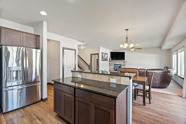 9414 W Ballesteros Ct, Cheney, WA 99004 - kitchen with stainless steel fridge, wood finished floors, a fireplace, dark brown cabinets, and a textured ceiling