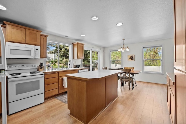 1626 5th St, Cheney, WA 99004 - kitchen with white appliances, light countertops, a chandelier, a center island, and light wood-style floors