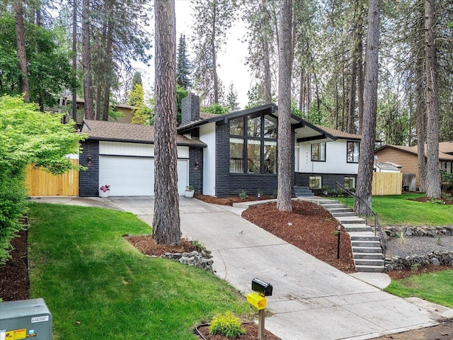 mid-century home featuring driveway, an attached garage, a chimney, and stairs