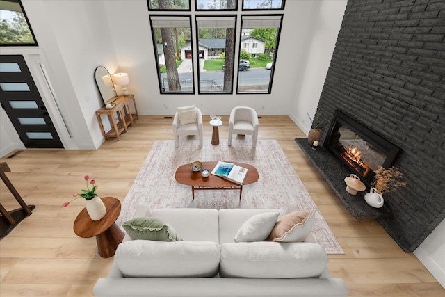 living area with a glass covered fireplace, wood finished floors, and baseboards