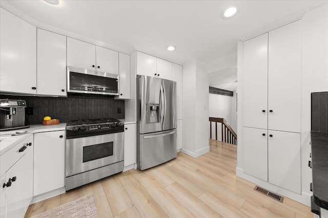 kitchen featuring appliances with stainless steel finishes, decorative backsplash, recessed lighting, light countertops, and white cabinets
