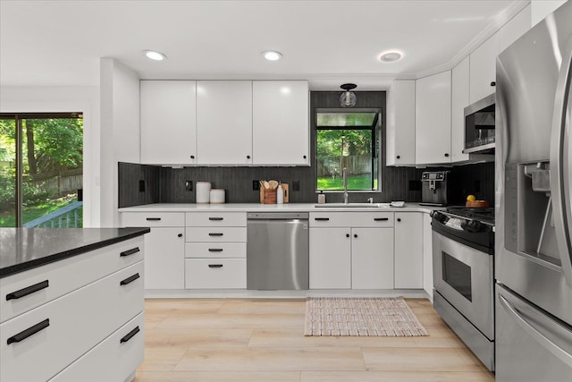 kitchen featuring appliances with stainless steel finishes, a sink, healthy amount of natural light, tasteful backsplash, and recessed lighting