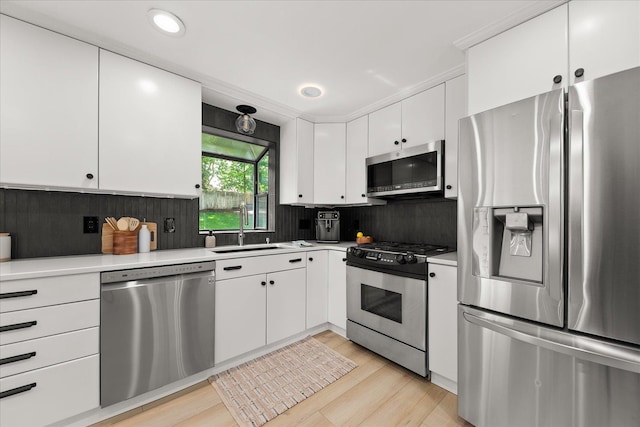 kitchen featuring stainless steel appliances, a sink, light countertops, decorative backsplash, and white cabinets
