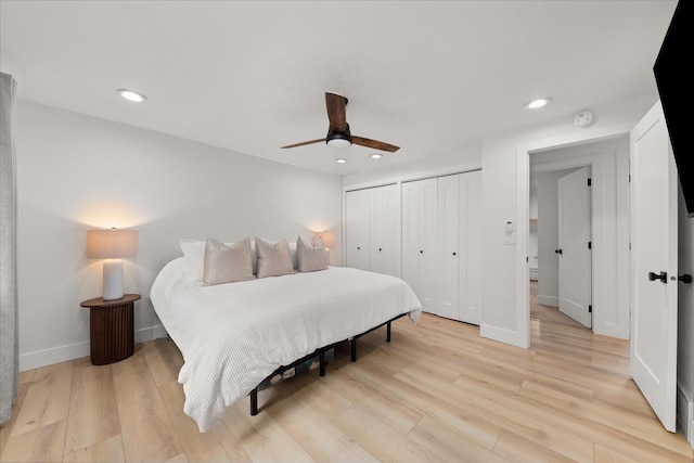 bedroom featuring two closets, recessed lighting, light wood finished floors, baseboards, and ceiling fan