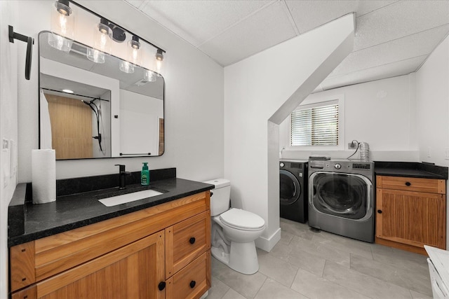 bathroom featuring washer and dryer, toilet, vanity, and tile patterned flooring