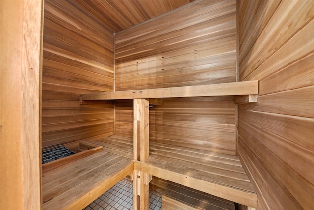 sauna with wood walls and tile patterned floors