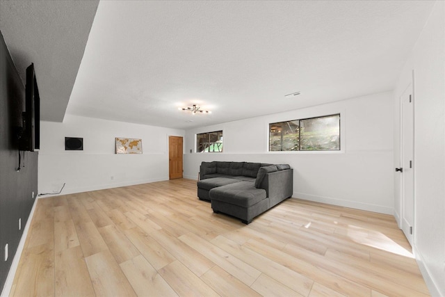 living area featuring light wood-style flooring, baseboards, and a textured ceiling