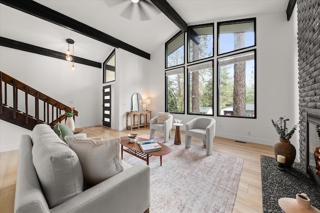 living room featuring beam ceiling, plenty of natural light, stairway, high vaulted ceiling, and baseboards