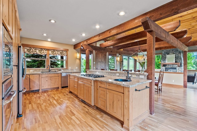 4224 E Hoffman Ln, Spokane, WA 99223 - kitchen with light brown cabinets, appliances with stainless steel finishes, light wood finished floors, recessed lighting, and a stone fireplace