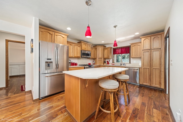kitchen with stainless steel appliances, dark wood-style flooring, a center island, a breakfast bar area, and recessed lighting