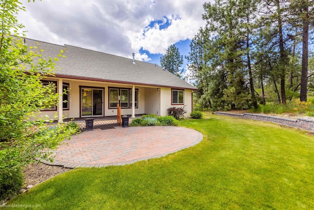 rear view of property with a patio area, a yard, and roof with shingles