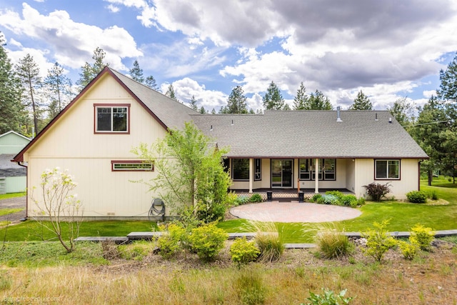 rear view of property featuring a shingled roof, a yard, and a porch