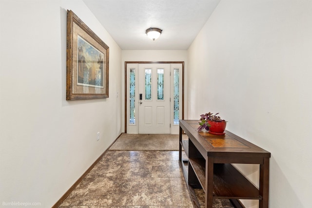 doorway to outside featuring baseboards and stone finish floors