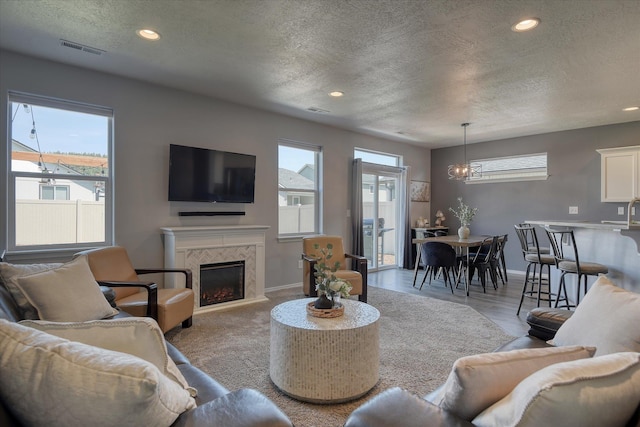 14621 E Sanson Ave, Spokane Valley, WA 99216 - living room featuring a textured ceiling, baseboards, recessed lighting, a fireplace, and a chandelier