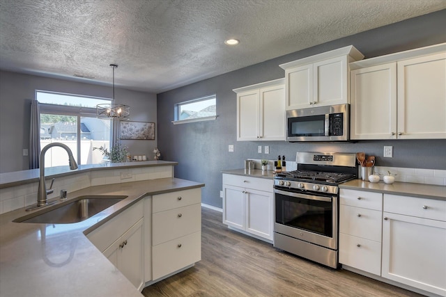 14621 E Sanson Ave, Spokane Valley, WA 99216 - kitchen with stainless steel appliances, a sink, a textured ceiling, wood finished floors, and white cabinets