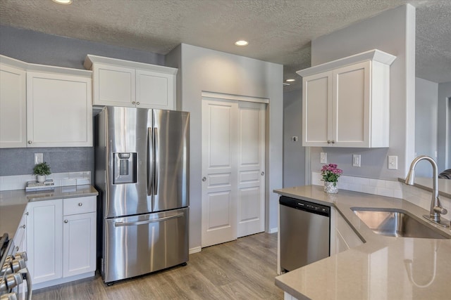14621 E Sanson Ave, Spokane Valley, WA 99216 - kitchen featuring stainless steel appliances, a sink, white cabinetry, light wood-style flooring, and a textured ceiling