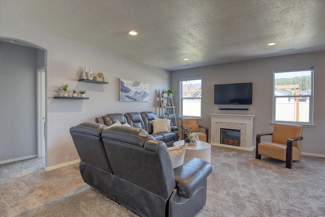 14621 E Sanson Ave, Spokane Valley, WA 99216 - carpeted living room with a textured ceiling, a glass covered fireplace, baseboards, arched walkways, and recessed lighting