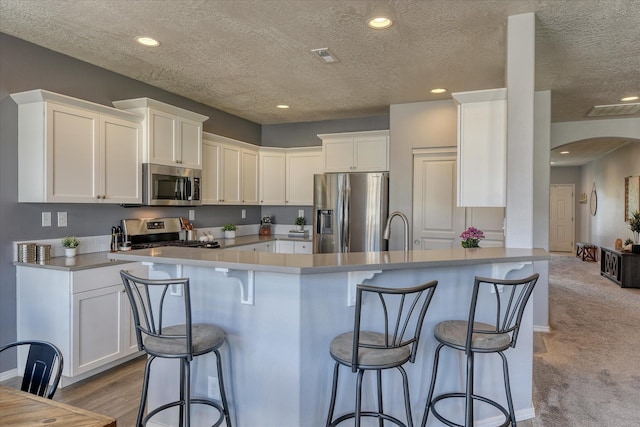 14621 E Sanson Ave, Spokane Valley, WA 99216 - kitchen with appliances with stainless steel finishes, arched walkways, white cabinetry, a textured ceiling, and recessed lighting