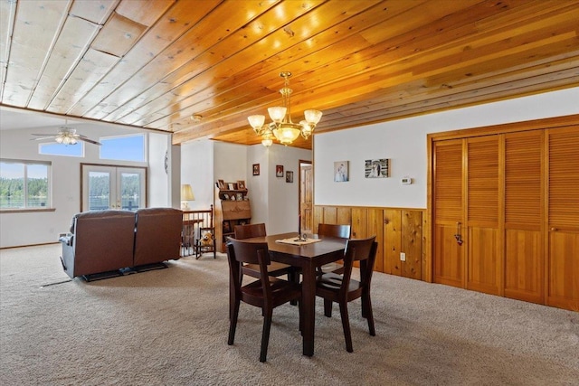 carpeted dining area featuring wood ceiling, a chandelier, a wainscoted wall, wooden walls, and ceiling fan