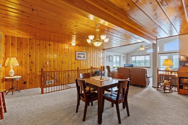 dining room featuring carpet flooring, wooden ceiling, a chandelier, ceiling fan, and wood walls