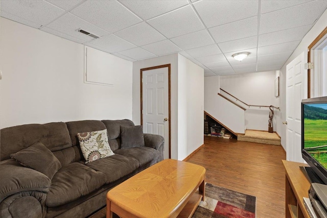 living area featuring wood finished floors, stairway, and a paneled ceiling