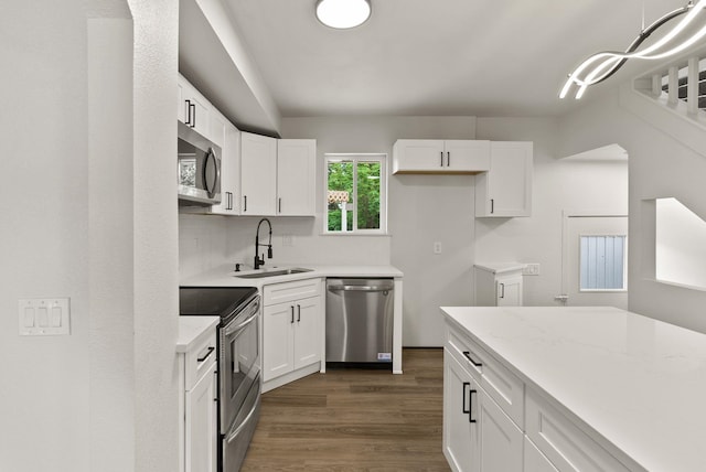 13704 E Heroy Ave, Spokane Valley, WA 99216 - kitchen with appliances with stainless steel finishes, a sink, white cabinets, dark wood-style floors, and decorative backsplash