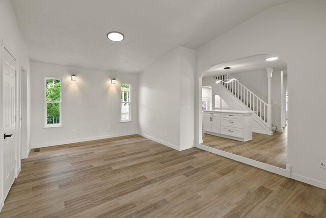 13704 E Heroy Ave, Spokane Valley, WA 99216 - unfurnished room with arched walkways, healthy amount of natural light, light wood-type flooring, baseboards, and lofted ceiling