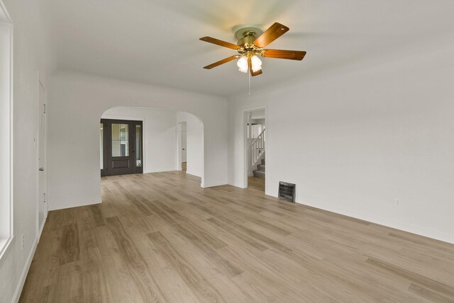 13704 E Heroy Ave, Spokane Valley, WA 99216 - unfurnished room with arched walkways, wood finished floors, stairs, ceiling fan, and baseboards