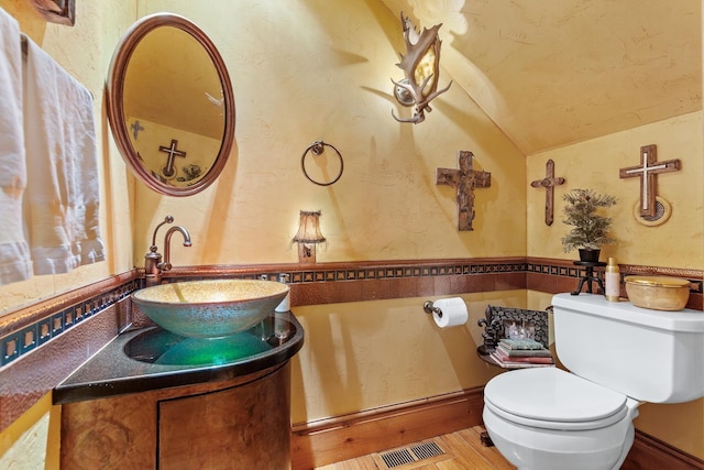 10351 N Gibson Rd, Hayden, ID 83835 - half bathroom featuring lofted ceiling, toilet, vanity, a textured wall, and wood finished floors