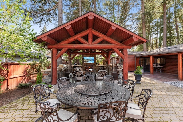 10351 N Gibson Rd, Hayden, ID 83835 - view of patio with fence, a gazebo, an outdoor stone fireplace, and outdoor dining space