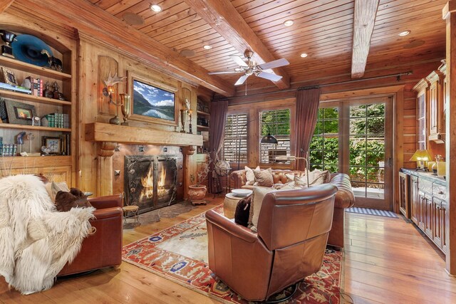 10351 N Gibson Rd, Hayden, ID 83835 - living room with wooden walls, light wood-style flooring, wooden ceiling, beam ceiling, and a premium fireplace