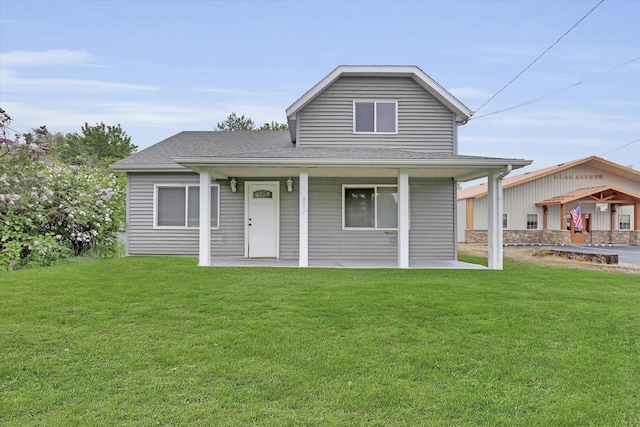 view of front facade with a front lawn, a shingled roof, and a porch