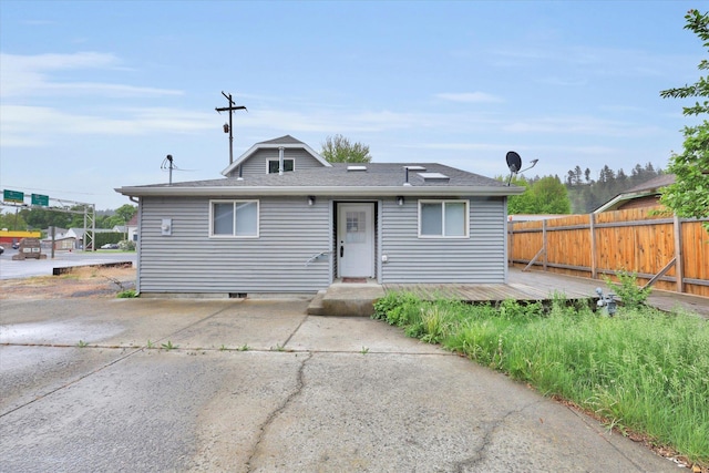 bungalow featuring fence, a deck, and roof with shingles