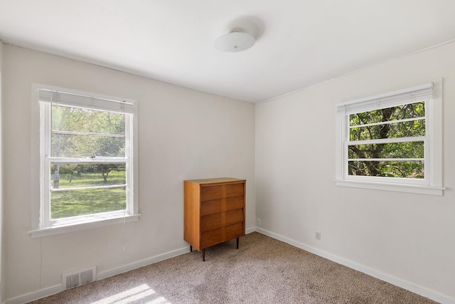 carpeted spare room featuring plenty of natural light and baseboards