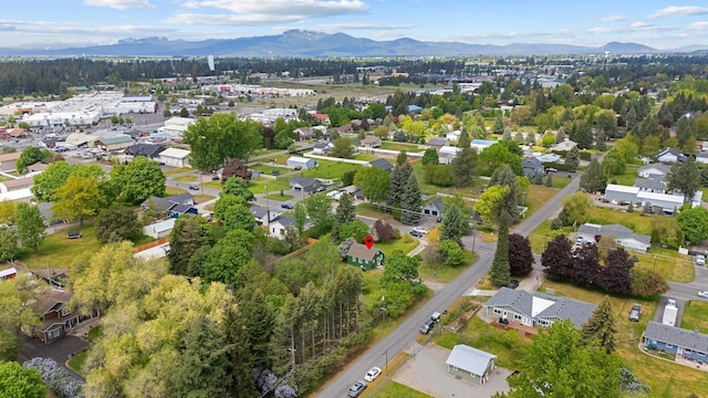 aerial view of property and surrounding area featuring a mountain backdrop and nearby suburban area