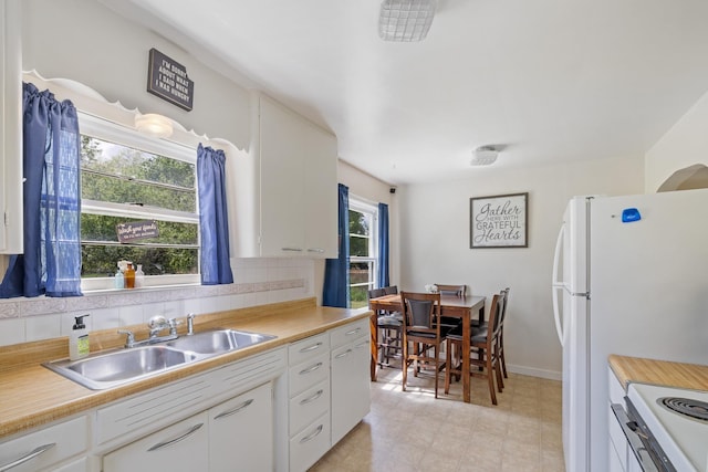 kitchen with a sink, white appliances, light countertops, and white cabinets
