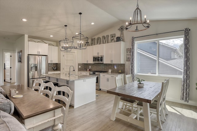 25523 N N Sheridan Rd, Chattaroy, WA 99003 - kitchen with appliances with stainless steel finishes, a chandelier, decorative backsplash, a center island with sink, and light stone countertops