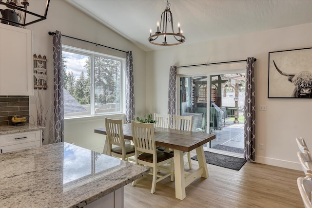 25523 N N Sheridan Rd, Chattaroy, WA 99003 - dining space featuring a chandelier, vaulted ceiling, light wood-style floors, and baseboards